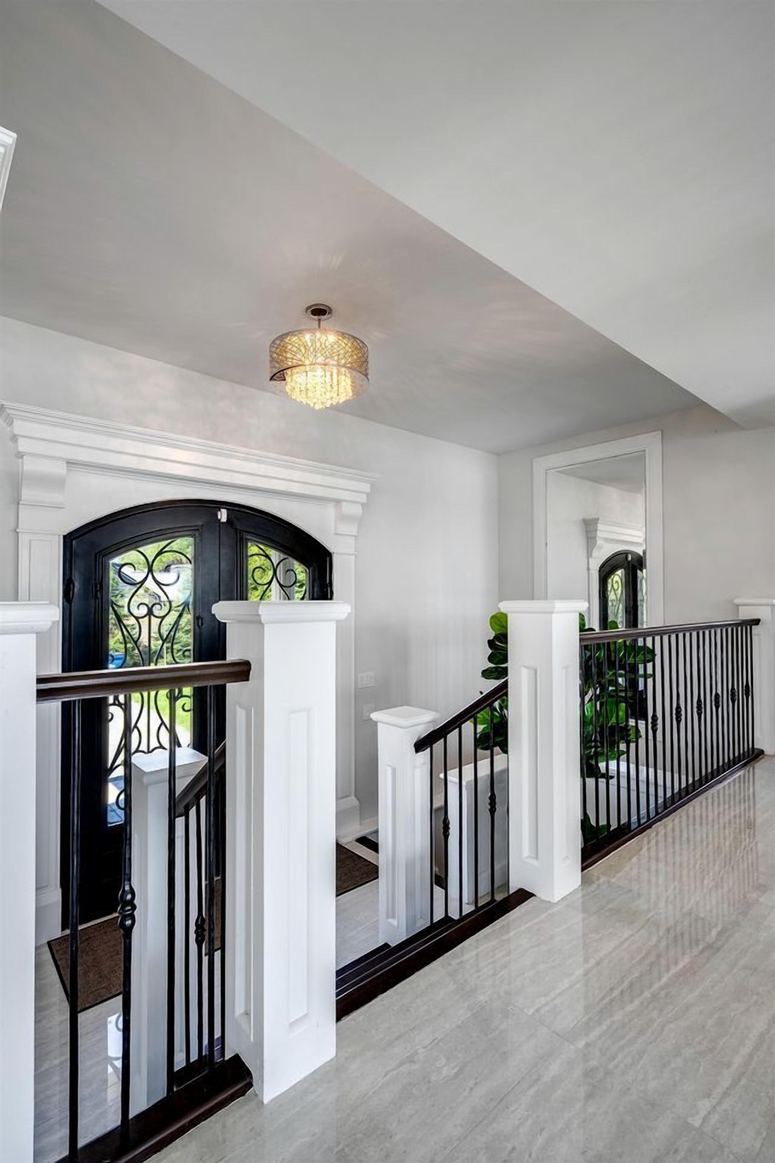 Ein modernes Interieur mit Treppe, weißen Wänden und einer Kristallleuchter.