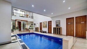 Una piscina interior amplia con vistas despejadas a la zona de la piscina, puertas de madera y un balcón con barandillas.