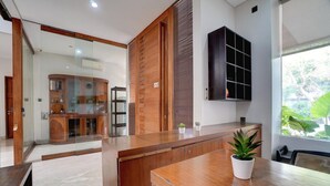 Un interior moderno con un mostrador de recepción de madera, un separador de vidrio y vistas al exterior.