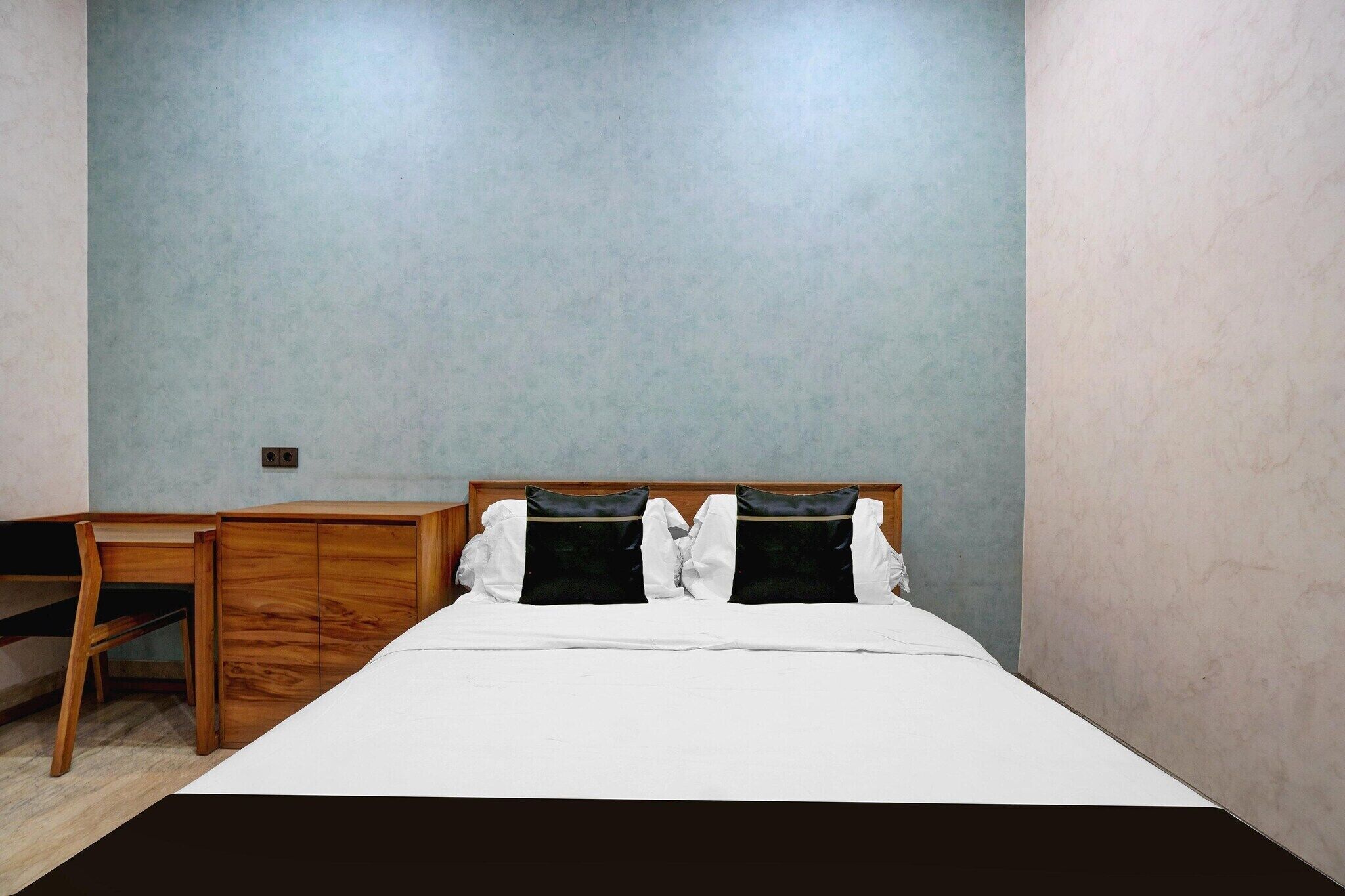 A bedroom with a bed, a wooden desk, and a chair.