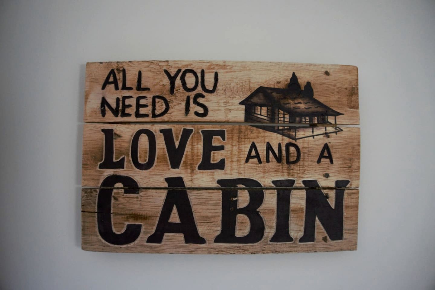 Ein Holzschild mit dem Schriftzug 'Alles was man braucht ist Liebe und eine Hütte'.