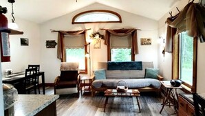 Interior acolhedor de uma cabana com uma cama, uma mesa de jantar e uma cozinha.