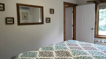 Um quarto com uma cama, um espelho grande e uma porta que dá para outro cômodo.