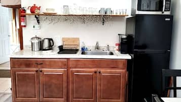 A kitchen with wooden cabinets, a black refrigerator, a coffee maker, and a microwave.