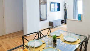 Zona pranzo con tavolo in vetro, sedie e tavolo per buffet con frutta e bevande.