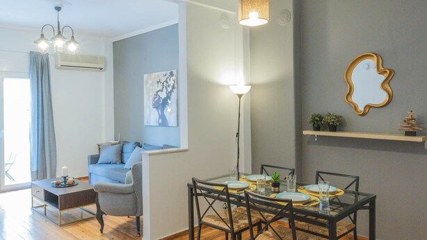 Un soggiorno moderno con zona pranzo, pavimento in legno, un divano, un tavolino da caffè e un lampadario.