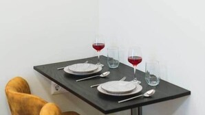 Un comedor con una mesa dispuesta para dos personas, una instalación artística moderna en la pared y una esquina con una silla.