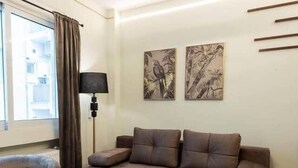 Una sala moderna con un sofá, una mesa de centro, una lámpara de pie y obras de arte en la pared.