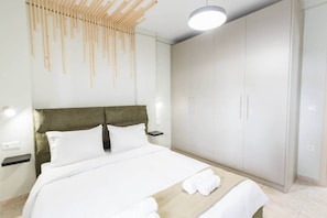 Ein Schlafzimmer mit Bett, Kleiderschrank, Nachttisch und einer Pendelleuchte.