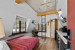 A bedroom with a lofted sleeping area, a desk, and a kitchenette. - Rustic A-Frame Cabins with Modern Amenities near Garden of the Gods in Colorado Springs, Colorado (Colorado Springs)