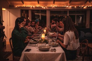 Un grupo de personas cenando en una mesa con velas, rodeado de luces de cadena.