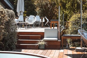 Una terraza de madera con mobiliario exterior, incluyendo sillas y una mesa.