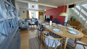 Uma sala de jantar com uma mesa de madeira posta para quatro pessoas, rodeada por cadeiras.