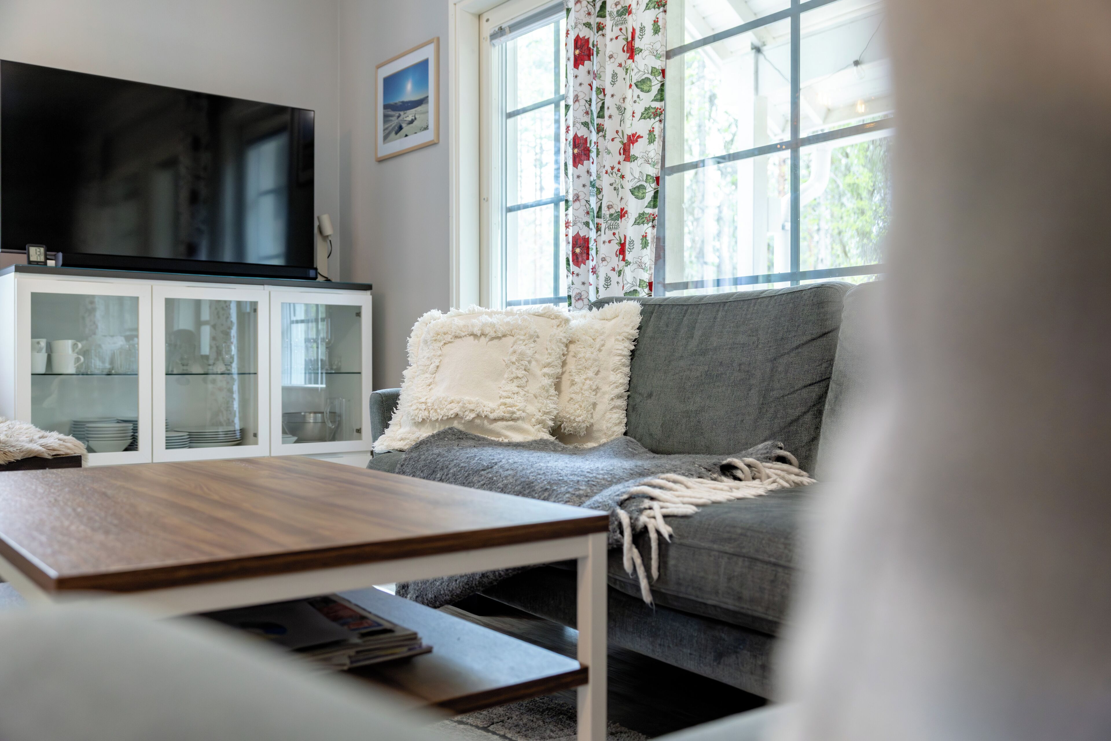 A living room with a television, a sofa, a coffee table, and a cabinet.