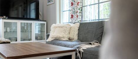 A living room with a television, a sofa, a coffee table, and a cabinet.