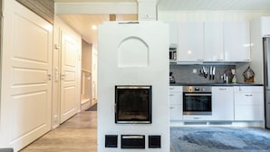 A modern kitchen with white cabinets, a built-in oven, and a fireplace.