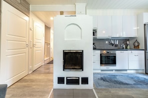 Una cocina moderna con armarios blancos, horno empotrado y chimenea.