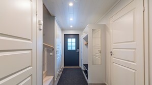 A hotel hallway with white doors, a dark carpet, and a window at the end.