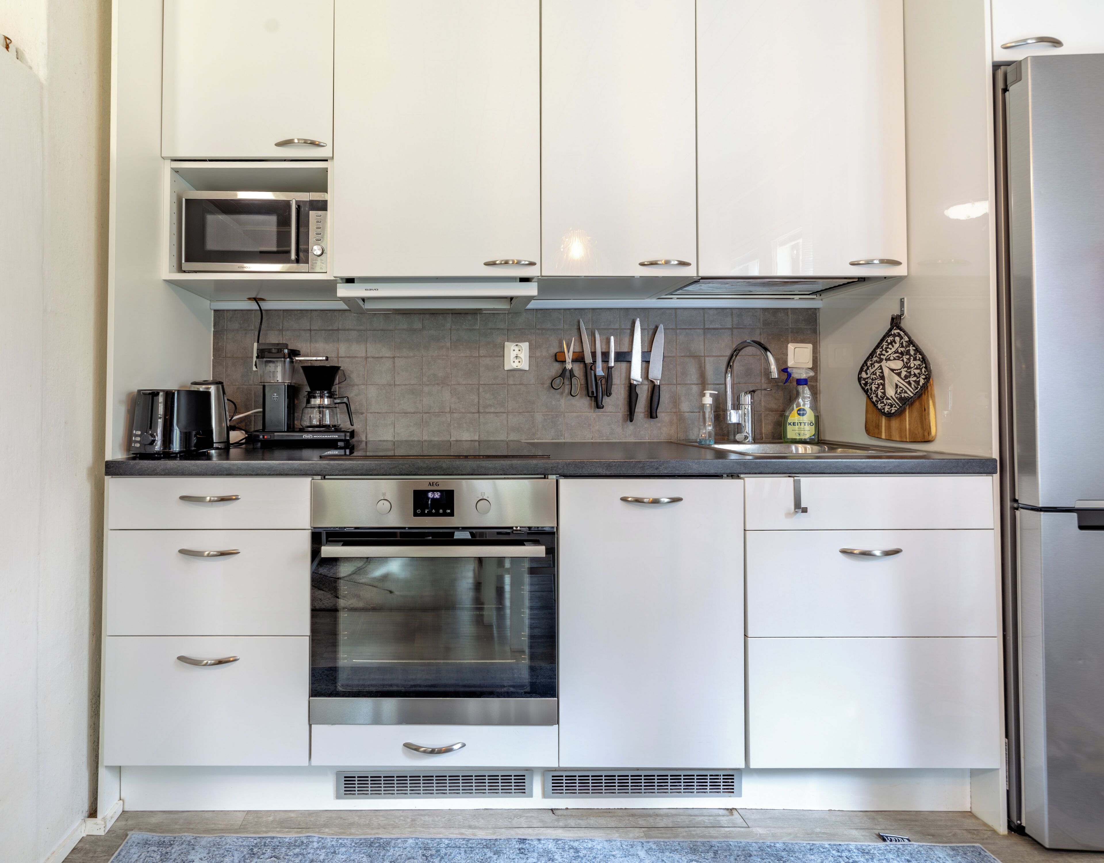 Una cucina moderna con mobili bianchi, elettrodomestici in acciaio inossidabile e forno a microonde integrato.