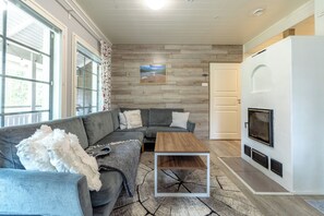 A modern living room with a sectional sofa, a coffee table, a fireplace, and a large window.