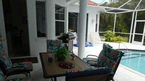 Eine Terrasse mit Pool, Gartenmöbeln und Grill.