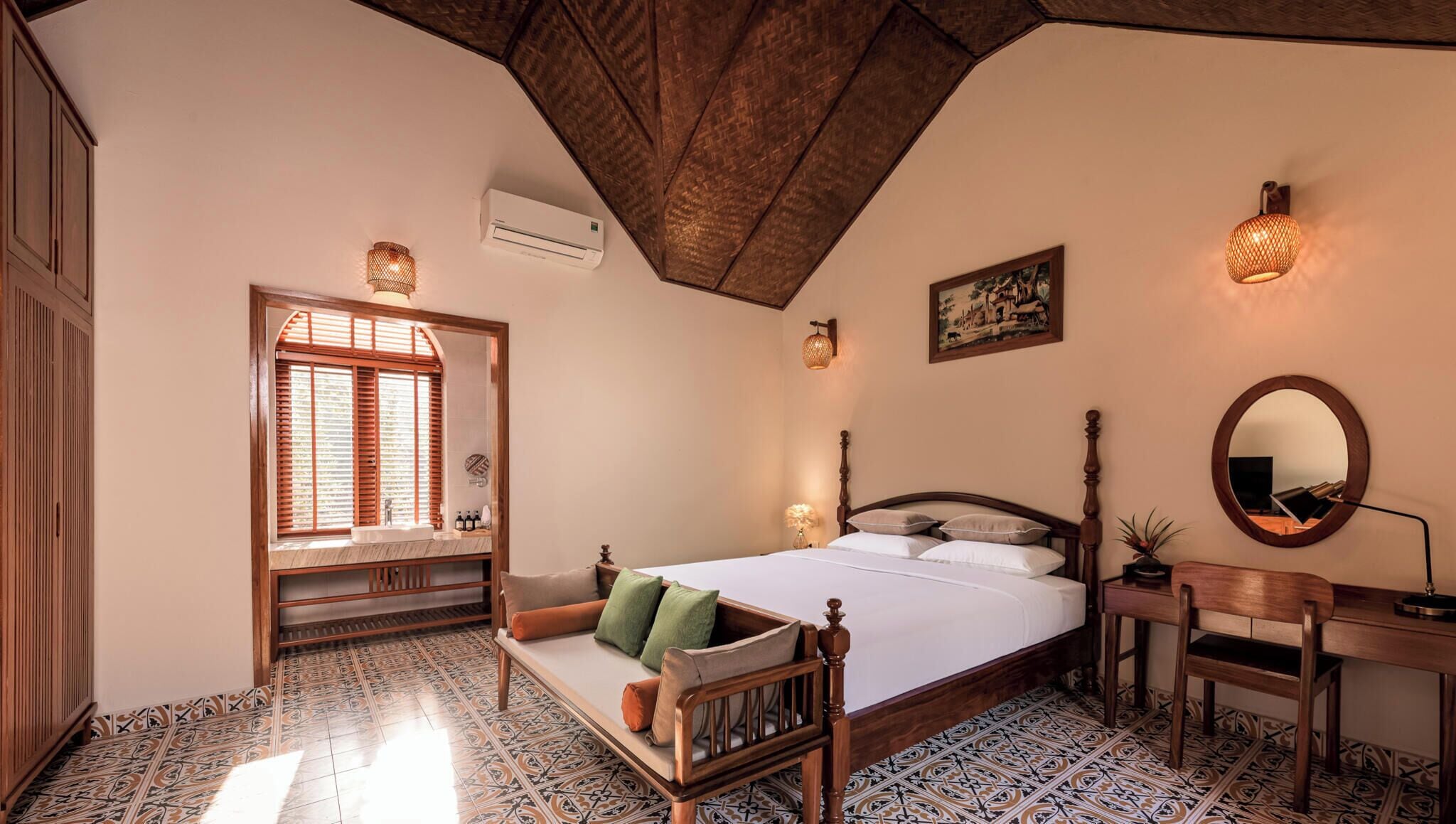 Une chambre à coucher comprenant un lit, une table de chevet, une chaise, un bureau, un miroir et une fenêtre avec des volets.