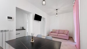A modern kitchen with white cabinets, a black countertop, and a flat-screen TV mounted on the wall. - Apartment 'Nora' with Shared Garden, Wi-Fi and Air Conditioning (Polpenazze del Garda)