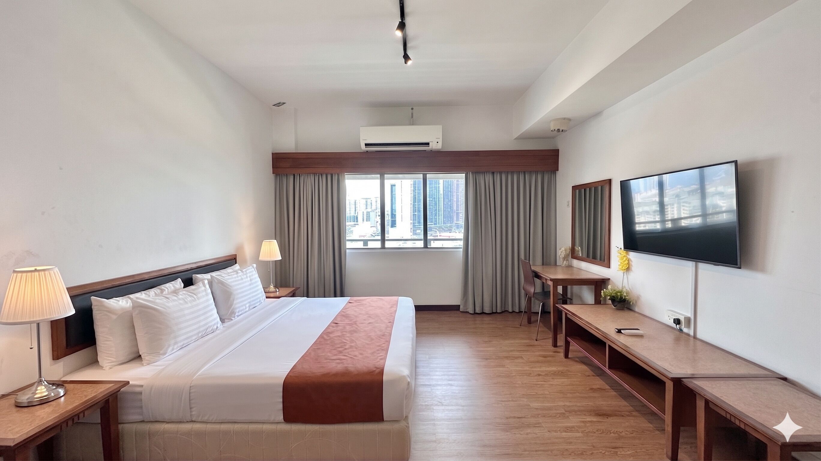 Una camera d'albergo con un letto, comodini, una scrivania, una televisione e una finestra con tende.