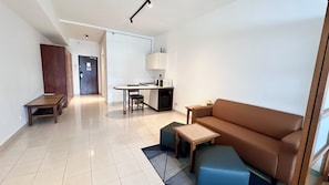 Una sala moderna con sofá, una mesa de centro, una mesa de comedor y una zona de cocina.