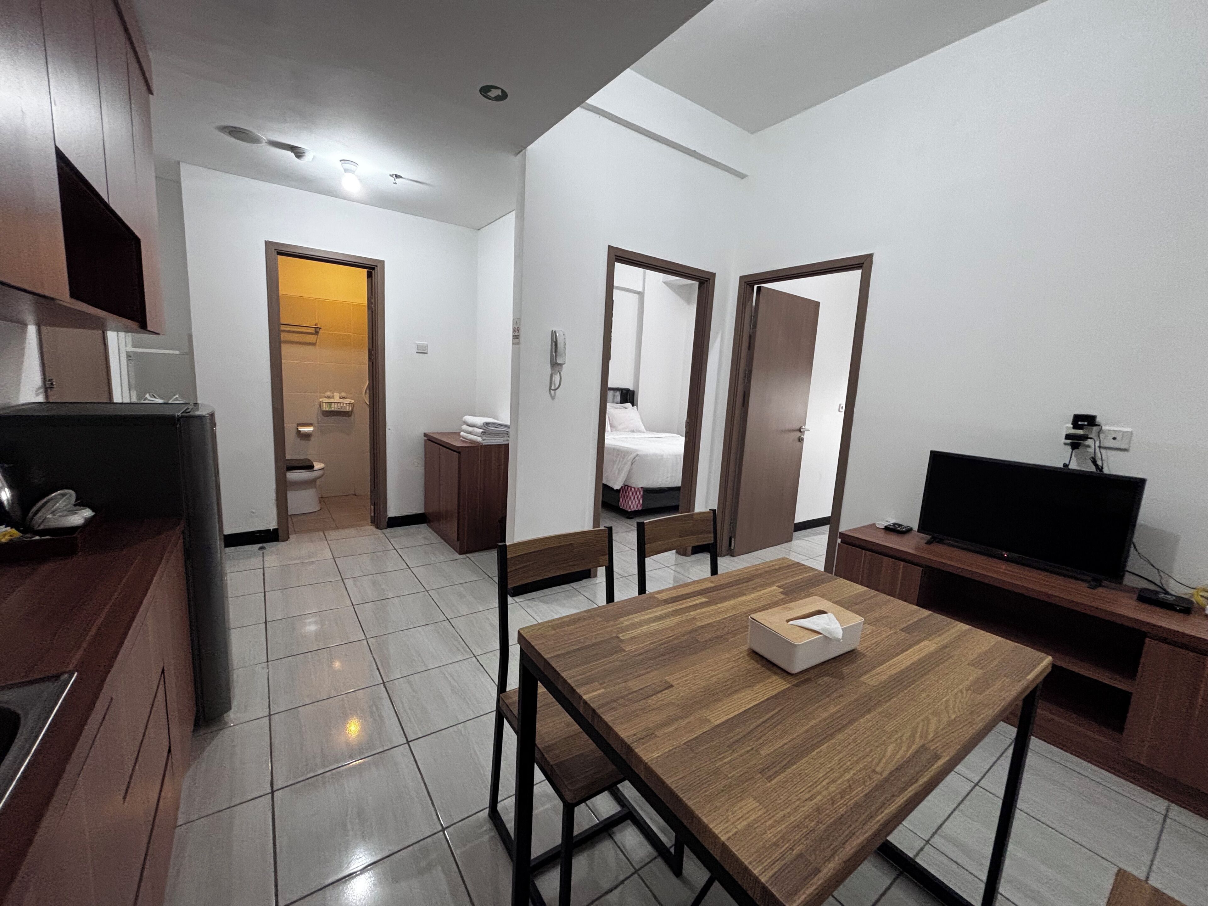 Een compacte hotelkamer met een houten eettafel, een televisie en een kitchenette.