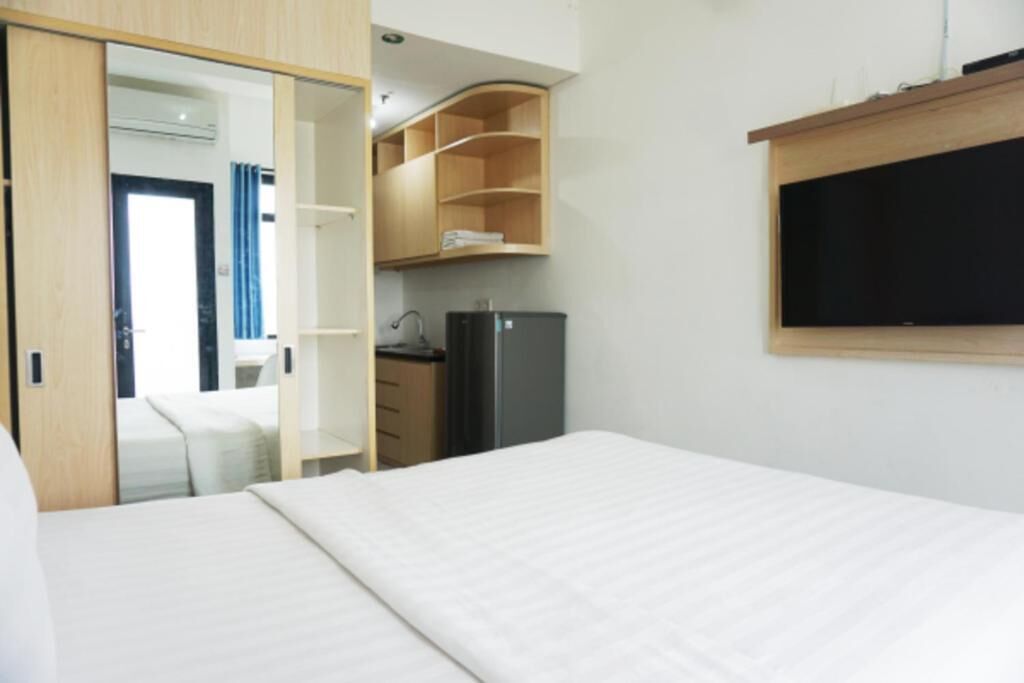 Een hotelkamer met een bed, een kledingkast, een klein keukenhoekje en een televisie.