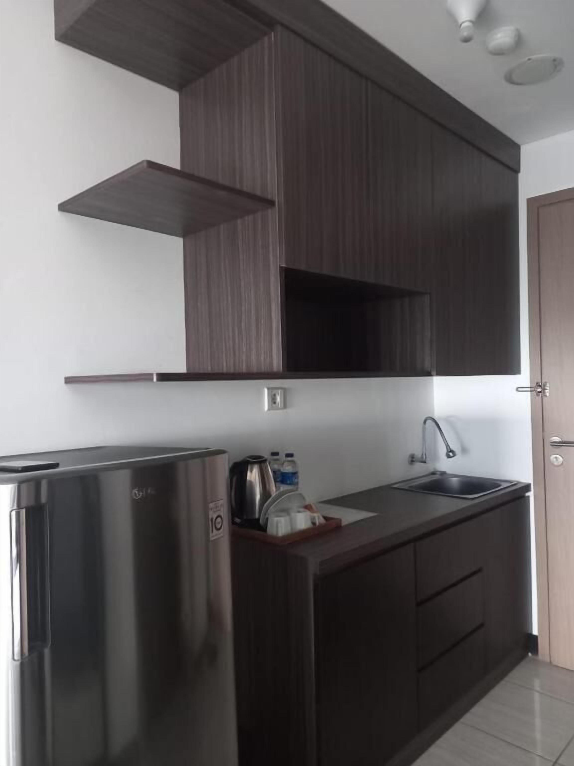 Cozinha moderna com armários escuros, geladeira de aço inoxidável e uma pia.
