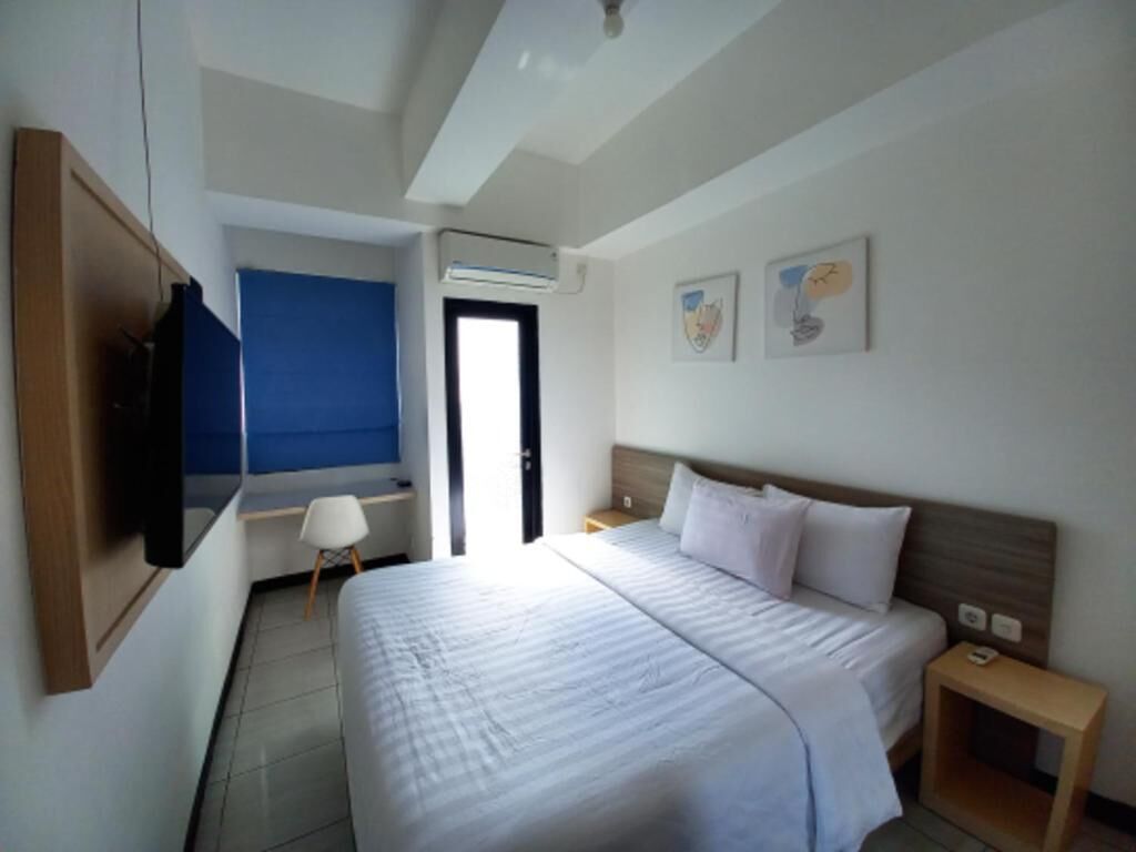 Een hotelkamer met een bed, een bureau, een stoel, een televisie en een raam.