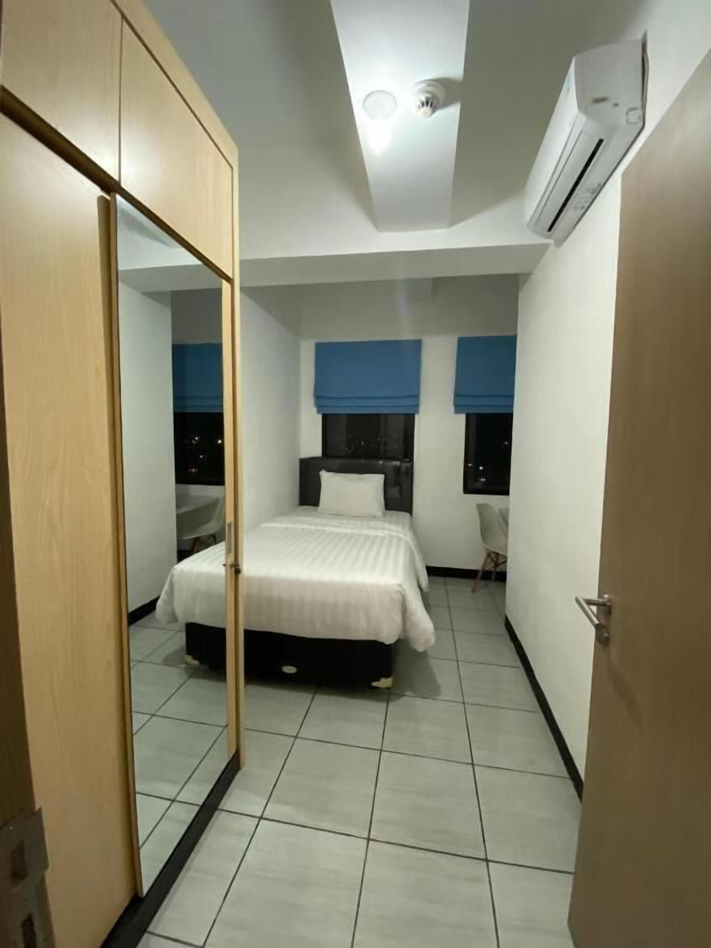 Een slaapkamer met een bed, een kledingkast, een spiegel en een airconditioning.