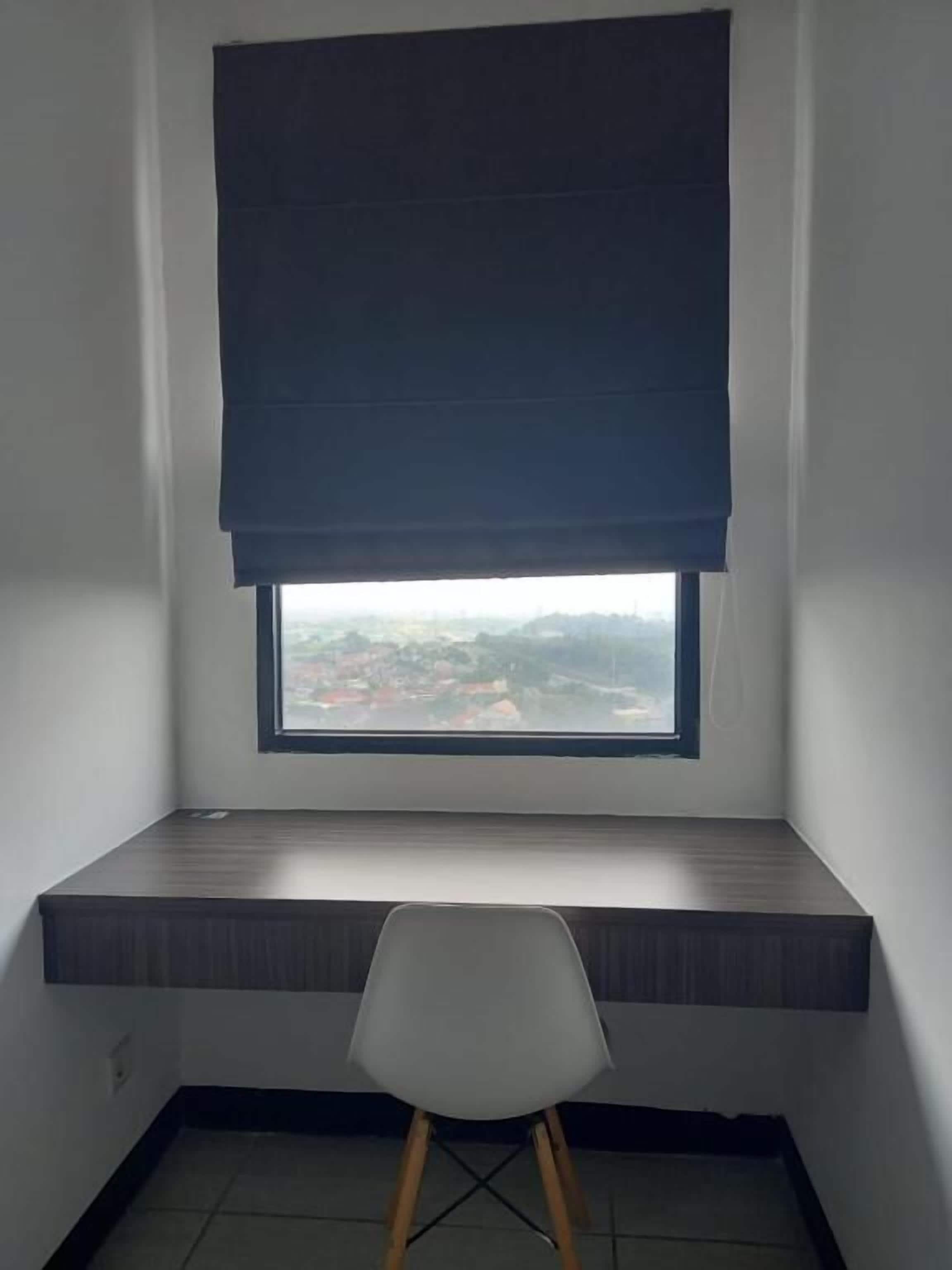 Una stanza angolare con finestra, una scrivania e una sedia.