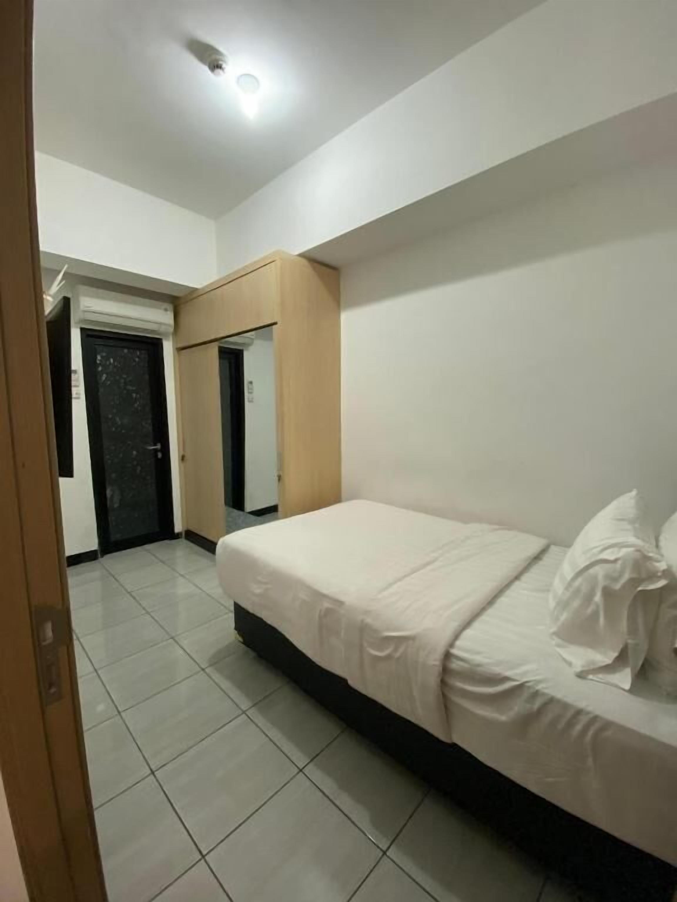 A bedroom with a bed, a door, and a light fixture.