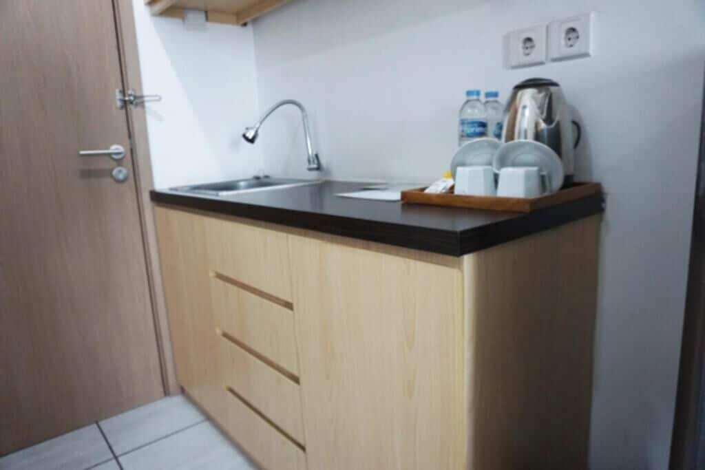 Une cuisine de taille réduite, équipée d’un évier, de meubles de rangement en bois et d’un plan de travail.