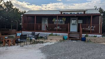 A rustic cabin with a porch, outdoor seating, and a gravel driveway.