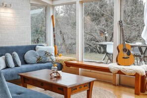 A cozy living room with a blue sofa, wooden coffee table, and a guitar. - Tranquil Vacation Rental by Lake Wakatipu with Majestic Mountain Views in Queenstown, New Zealand (Queenstown)