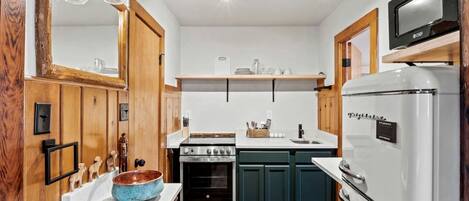 A compact kitchen with wooden cabinets, a white refrigerator, a stove, and a microwave.