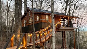 Eine Holzhütte mit einer Terrasse und einer Treppe, umgeben von Bäumen.