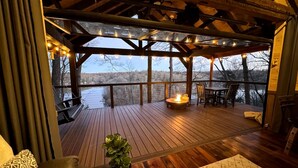 Eine Holzterrasse mit Feuerstelle, Sitzgelegenheiten und Blick auf eine verschneite Landschaft.