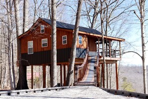 A wooden cabin with a balcony and a staircase leading to a deck.