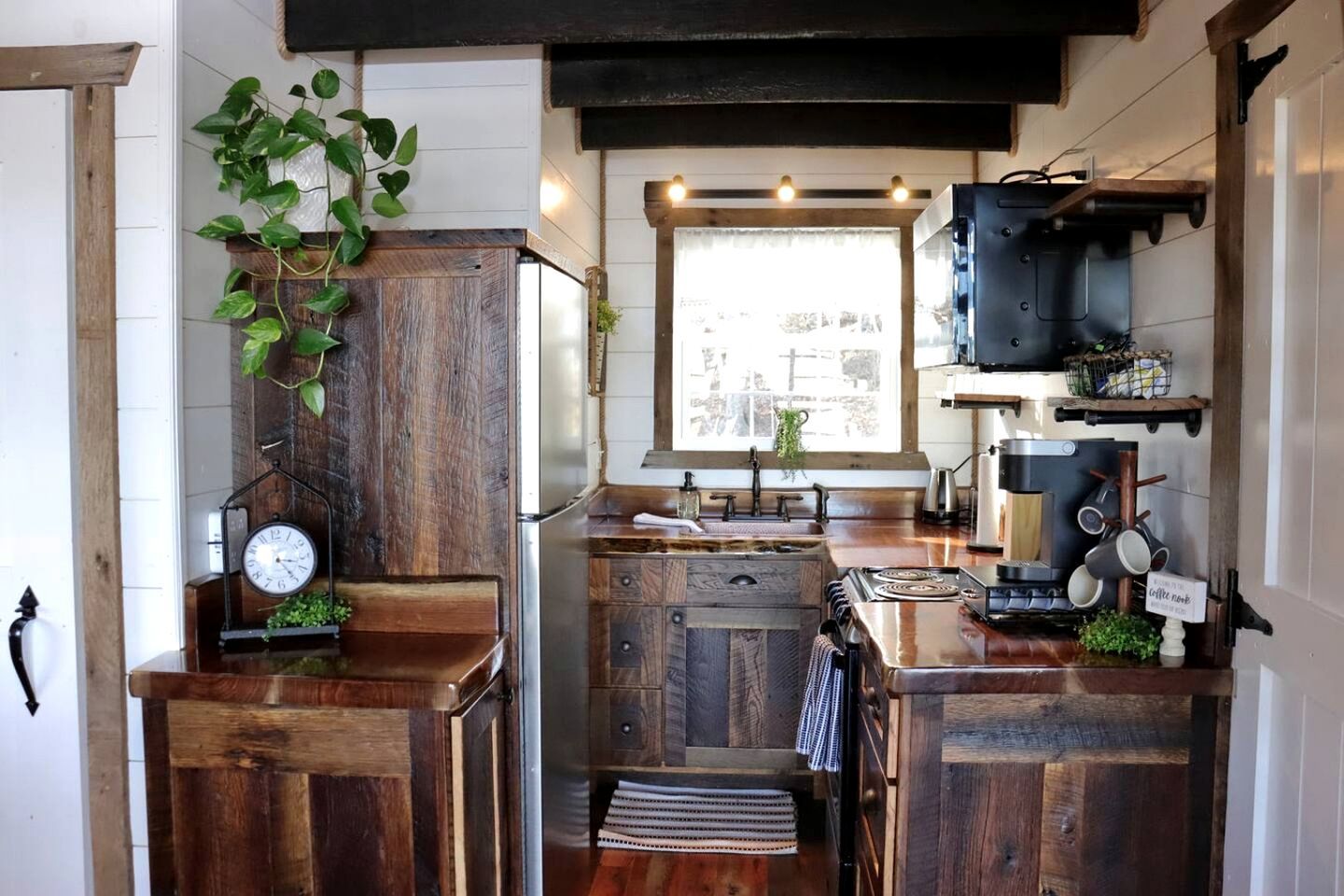 A compact kitchen with wooden cabinetry, a built-in stove, a sink, and a window with a view.
