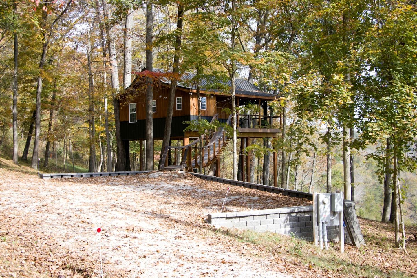 A cabin with a wooden exterior, elevated on stilts, surrounded by trees.