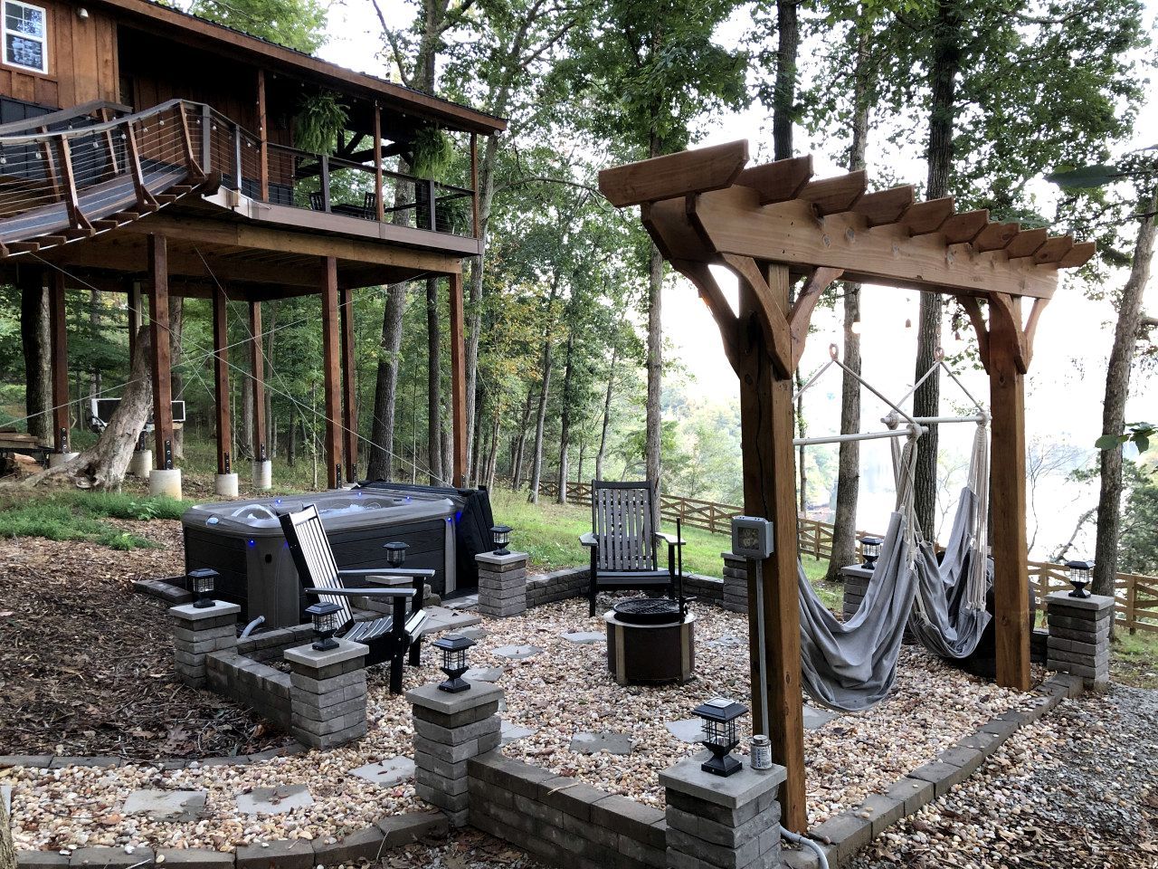 Une terrasse en bois avec un barbecue, des sièges d’extérieur et des hamacs.