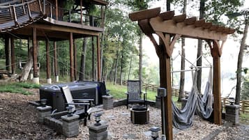 Une terrasse en bois avec un barbecue, des sièges d’extérieur et des hamacs.