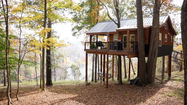 Ein Baumhaus mit Balkon, umgeben von Herbstlaub.