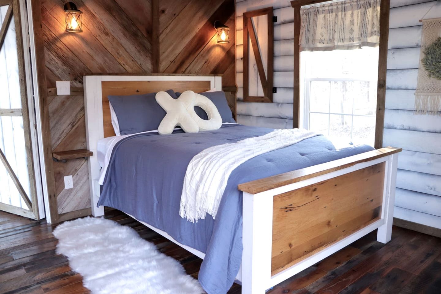 A wooden cabin-style bedroom with a bed, pillows, and a white furry rug.