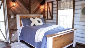 Ein Schlafzimmer im Chalet-Stil mit einem Bett, Kissen und einem weißen, flauschigen Teppich.